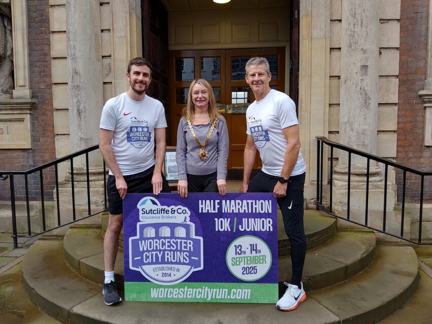 Three people stood with a Worcester City Runs banner
