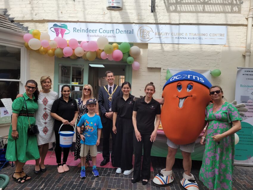 People all stood in a line with an Acorns mascot and fundraising bucket