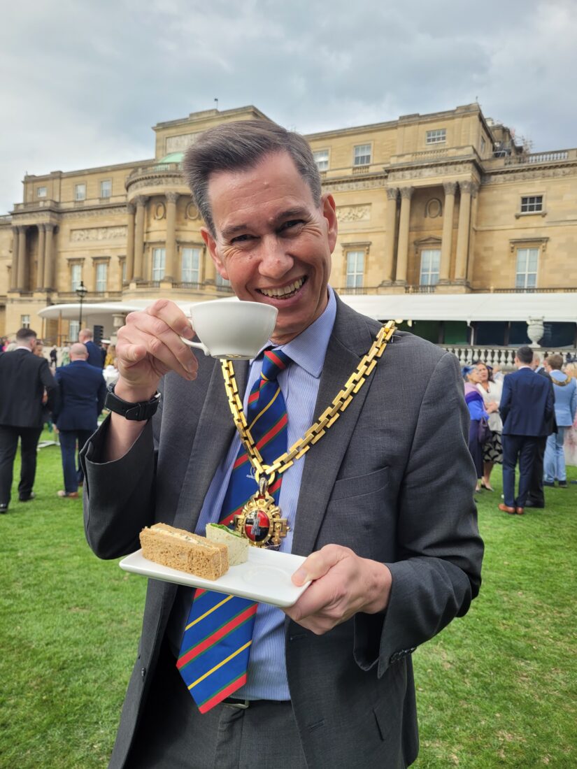 The Mayor holding a tea cup in the grounds of Buckingham Palace