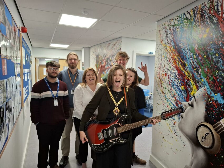 Tor Pingree plating a guitar with students and teachers 